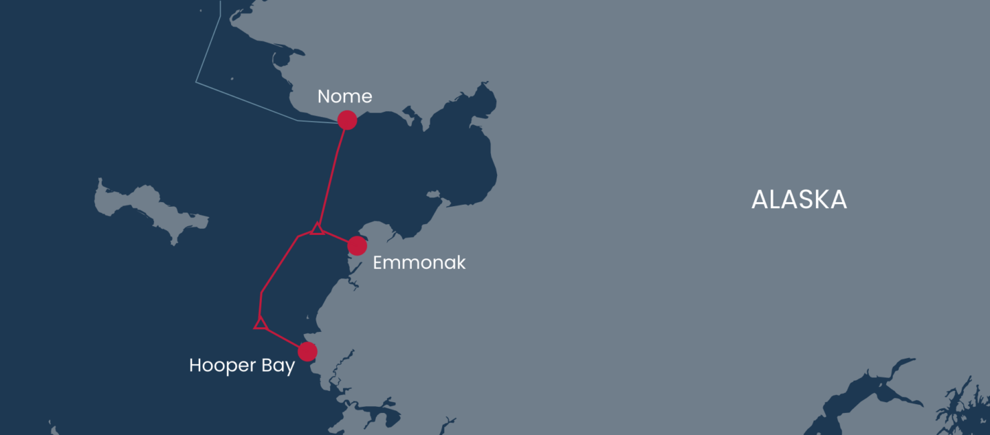 Map showing a red route connecting Nome, Emmonak, and Hooper Bay in western Alaska