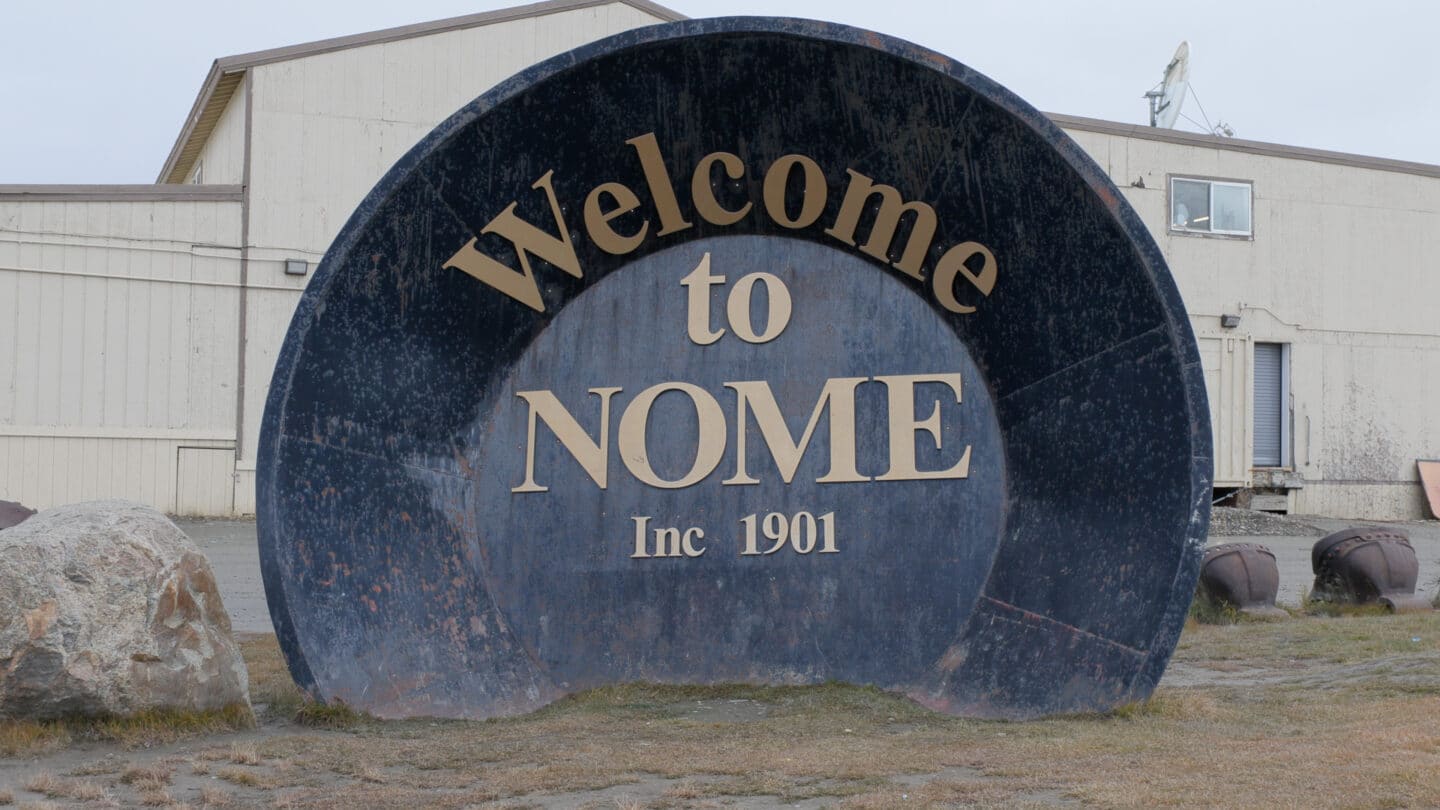 Large metal sign reading Welcome to Nome Inc 1901 in an outdoor town setting